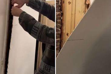 Man peels back plasterboard and reveals yellow door beneath. 