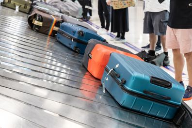 Baggage luggage at airport arrival carousel with passengers patiently awiating to claim theirs