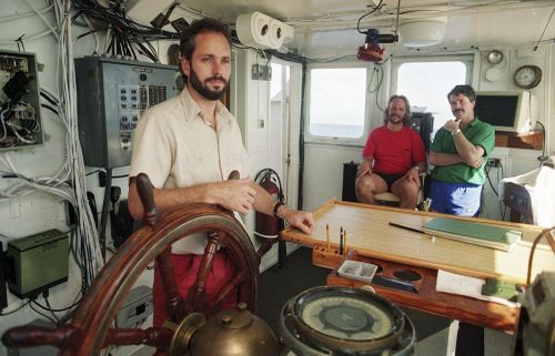 FILE - In this Aug. 29, 1991, file photo, Tommy Thompson, left, stands at the helm of the Arctic Explorer as Bob Evans, center, and Barry Schatz look on in Norfolk, Va. Thompson, a former deep-sea treasure hunter, is about to celebrate his fifth year in jail for refusing to disclose the whereabouts of 500 missing coins made from gold found in an historic ship wreck. Despite an investors lawsuit and a federal court order, Thompson still won't cooperate with authorities trying to find thos