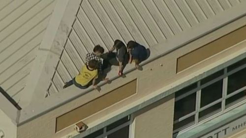 The four protesters on top of Tony Abbott's Manly electoral office. (9NEWS)