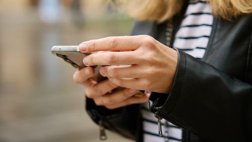 Close up shot of woman using smartphone on city street. Mobile phone in female hands outdoors