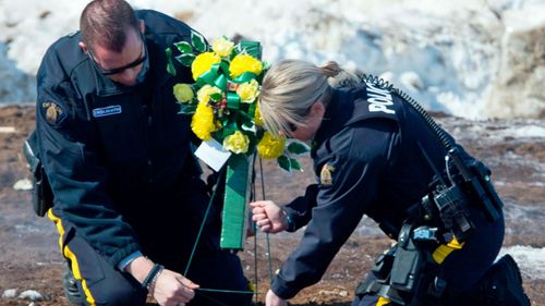 Members of the Royal Canadian Mounted Police lay flowers at the intersection of a crash site near Tisdale, Saskatchewan. (AP).