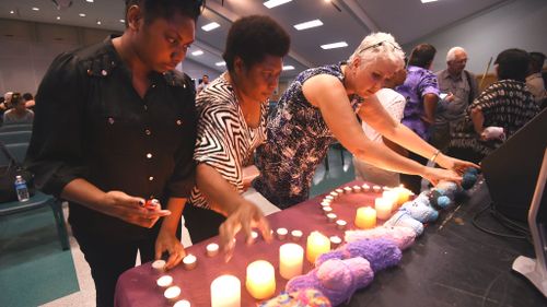 Mourners light candles at a service for the children dead in an alleged knife attack in Cairns. (AAP)