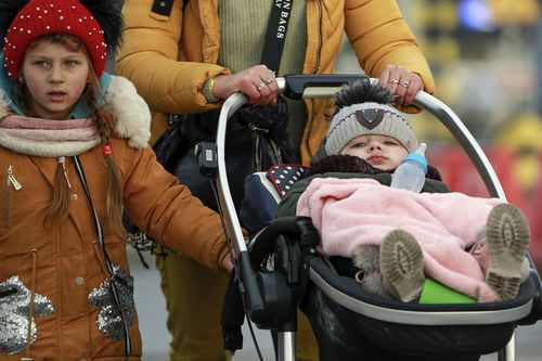 Ukranian refugee mother pushes her baby in a trolley as they arrive at the Medyka border crossing, Poland, Saturday, Feb. 26, 2022. (AP Photo/Visar Kryeziu)