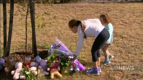 Local children laying flowers in tribute to the three children killed. (9NEWS)