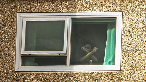 A man living in the Flemington Public housing flats is seen making a gesture with his arms crossed.