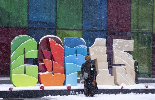 Des délégués prennent des photos souvenirs lors d'une chute de neige à l'extérieur du centre des congrès lors de la conférence COP15 des Nations Unies sur la biodiversité à Montréal.