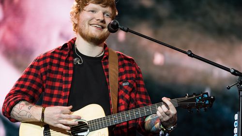 Ed Sheeran jouant de la guitare avec micro lors d'un concert 