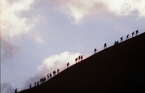 File photo shows tourists climbing Uluru at sunrise. 