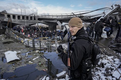 Des personnes marchent sous un pont détruit en fuyant Irpin, à la périphérie de Kiev, en Ukraine, le mardi 8 mars 2022. 