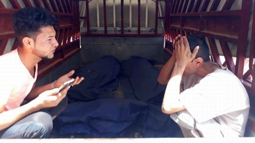 A grieving man by the bodies of three family members, including a baby. (Owen Holdaway)