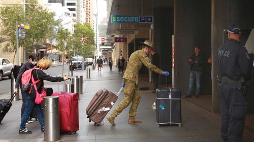 Australians returning from overseas are led into the Hilton Hotel in the Sydney CBD.