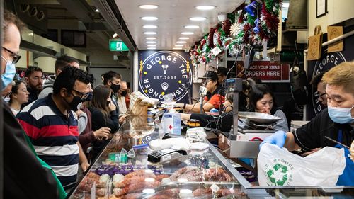 People wear a face mask as they shop at George the Fishgonger shop at the Queen Victoria Market in Melbourne, Australia.