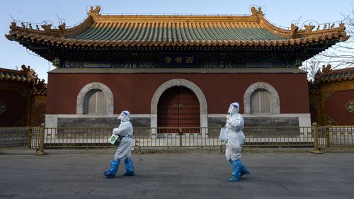 Epidemic control workers wear PPE as they walk by the Huangsi Temple on their way to perform nucleic acid tests on people under lockdown or health monitoring for COVID-19 on December 3, 2022 in Beijing, China. (Photo by Kevin Frayer/Getty Images)