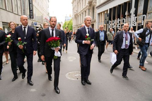 Norway's Crown Prince Haakon, center left, and Prime Minister Jonas Gahr Stoere, center right, visit the scene of a shooting in central Oslo, Norway, Saturday, June 25, 2022.