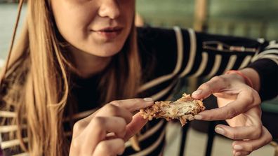 A young woman eating fried chicken