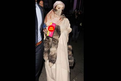 Lady Gaga descends on London Fashion Week, and as if wearing a burqa adorned with racoon tails isn't culturally insensitive enough, her purse has the bad C-word stitched onto it with sequins.