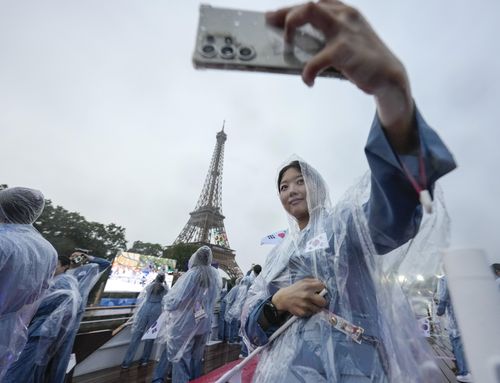 Asom Kim, a physiotherapist from team South Korea takes a selfie with the Eiffel Tower from a boat down the Seine River in Paris, France, during the opening ceremony of the 2024 Summer Olympics, Friday, July 26, 2024. 