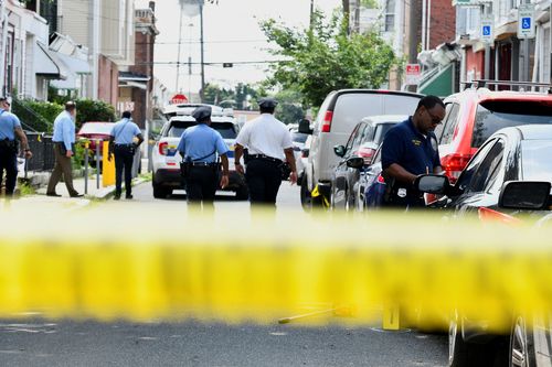 Police officers work at the scene as investigations are ongoing the day after a mass shooting in the Kingsessing section of southwest Philadelphia, Pennsylvania.