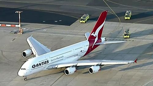 QF7 flanked by fire rescue trucks after landing safely. (9NEWS)