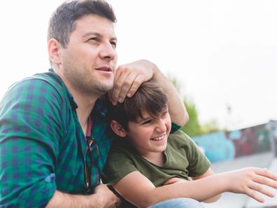 Man hugging boy and messing with his hair as the boy laughs