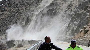 Two Chinese police officers run away from the site of an 8.1 magnitude aftershock on China National Highway 318 in southern Tibet. (AP)
