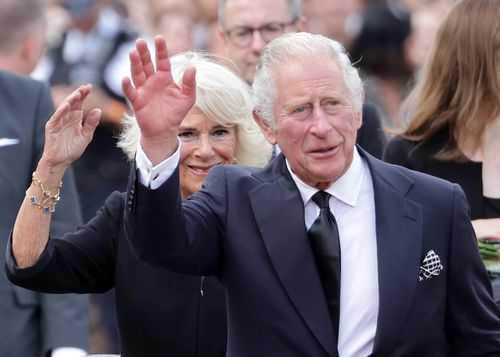 King Charles III and Camilla, Queen Consort wave after viewing floral tributes to the late Queen Elizabeth II outside Buckingham Palace on September 09, 2022
