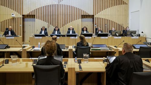 Presiding judge Hendrik Steenhuis, rear, fourth from left, opens the court session as the trial resumed at the high security court building at Schiphol Airport, near Amsterdam, Monday, June 8, 2020, for three Russians and a Ukrainian charged with crimes including murder for their alleged roles in the shooting down of Malaysia Airlines Flight MH17 over eastern Ukraine nearly six years ago.