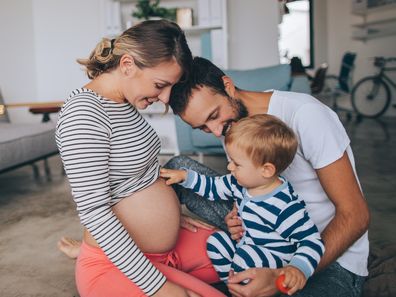 Photo of a little boy being curious about his mother's growing belly