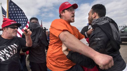 A supporter of President Donald Trump, center, clashes with an anti-Trump protester. (AAP)