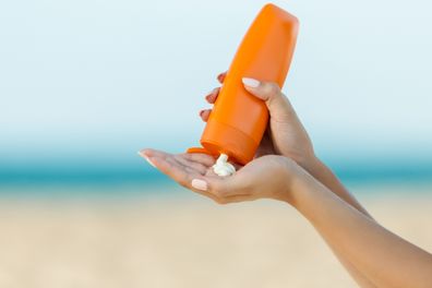 Woman's hand applies sunscreen on the beach