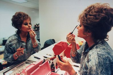 TV talk show host Tammy Faye Bakker Messner applying mascara to eyelashes in mirror in dressing room. (Photo by John Storey/Getty Images)