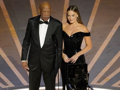 Morgan Freeman, left, and Margot Robbie speak about Warner Brothers 100 years anniversary at the Oscars on Sunday, March 12, 2023, at the Dolby Theatre in Los Angeles. (AP Photo/Chris Pizzello)
