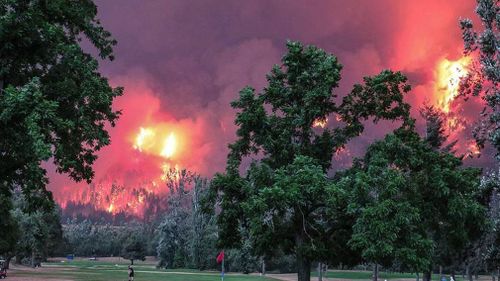 Golfers tee-off as the huge blaze burns through bush. (Facebook: Beacon Rock Golf Course)