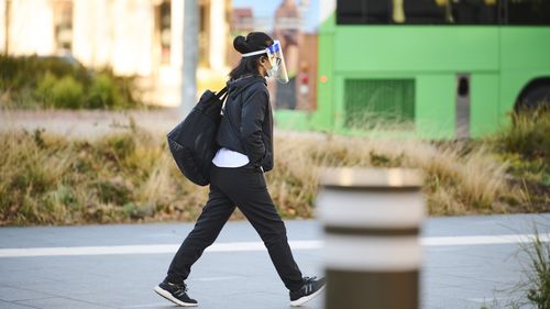 A pedestrian wearing a face shield and mask in Canberra.