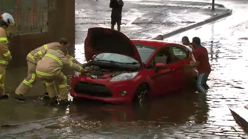 Firefighters pull a car from flood waters on York Street, South Melbourne. 