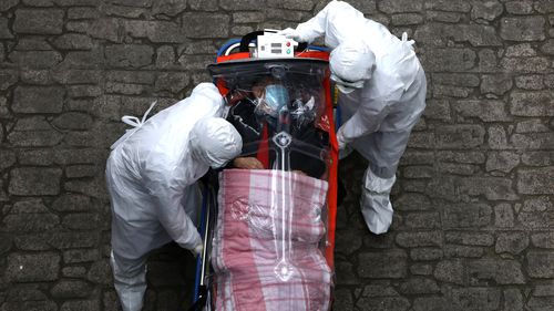 Medical staff, wearing protective gear, move a patient infected with the coronavirus from an ambulance to a hospital in Seoul, South Korea.