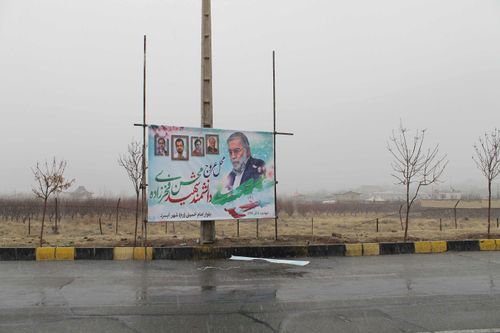 A poster of Mohsen Fakhrizadeh  stands above the spot where he was gunned down outside Tehran.