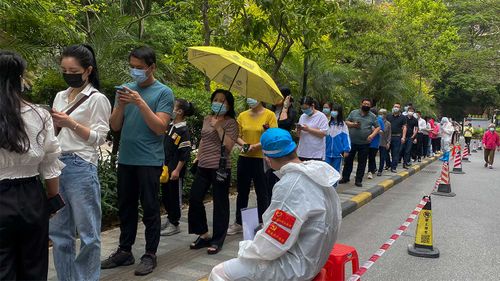 Workers in protective gear watch over residents line up for the COVID-19 test at a residential block in Guangzhou, China.