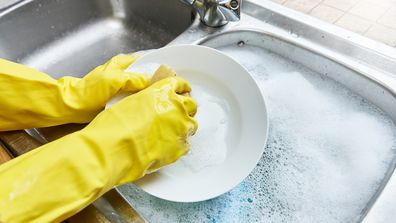 Wearing rubber gloves washing the dishes