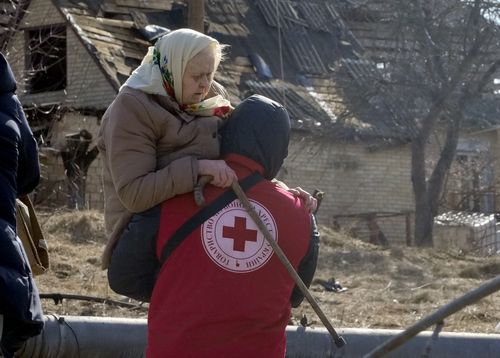 A Red Cross worker carries an elderly women during evacuation in Irpin, some 25 km  northwest of Kyiv, Friday, March 11, 2022. 