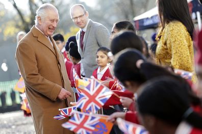 King Charles III smiles as he speaks with local school children waving flags during a visit to the newly built Guru Nanak Gurdwara, in Luton, England, Tuesday, Dec. 6, 2022.