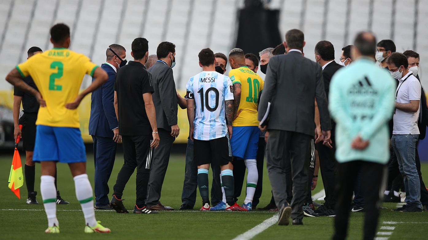 Lionel Messi of Argentina and Neymar Jr. of Brazil talk to health authorities as the match is delayed during a match between Brazil and Argentina.