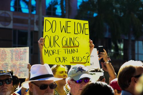 "Do we love our guns more than our kids", one sign read. (AAP)