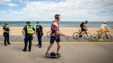 People cycle and skate along St Kilda beach in Melbourne as Victorian Police go on patrol. 