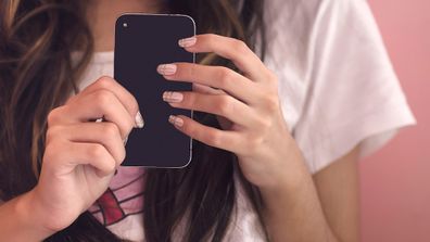 Young woman holding her smart phone, close-up