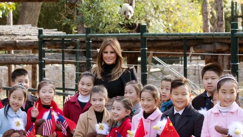 US First Lady Melania Trump poses for photos with Chinese children holding flags and the bald eagle dolls near the panda enclosure at a zoo in Beijing, China. (AAP)