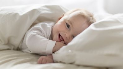 A happy baby laying in bed