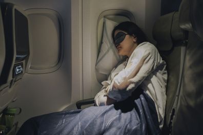 With her mask on to help her sleep, the woman gets good, deep sleep during her flight.