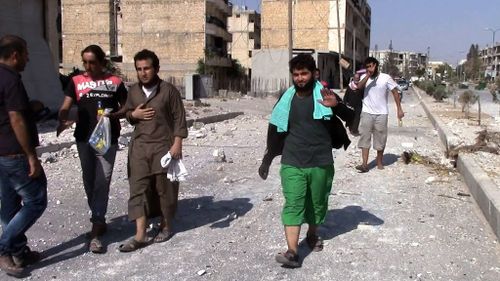 Syrians walk back to their homes through the streets of Manbij after Islamic State began to withdraw from the area on August 12. (AFP)